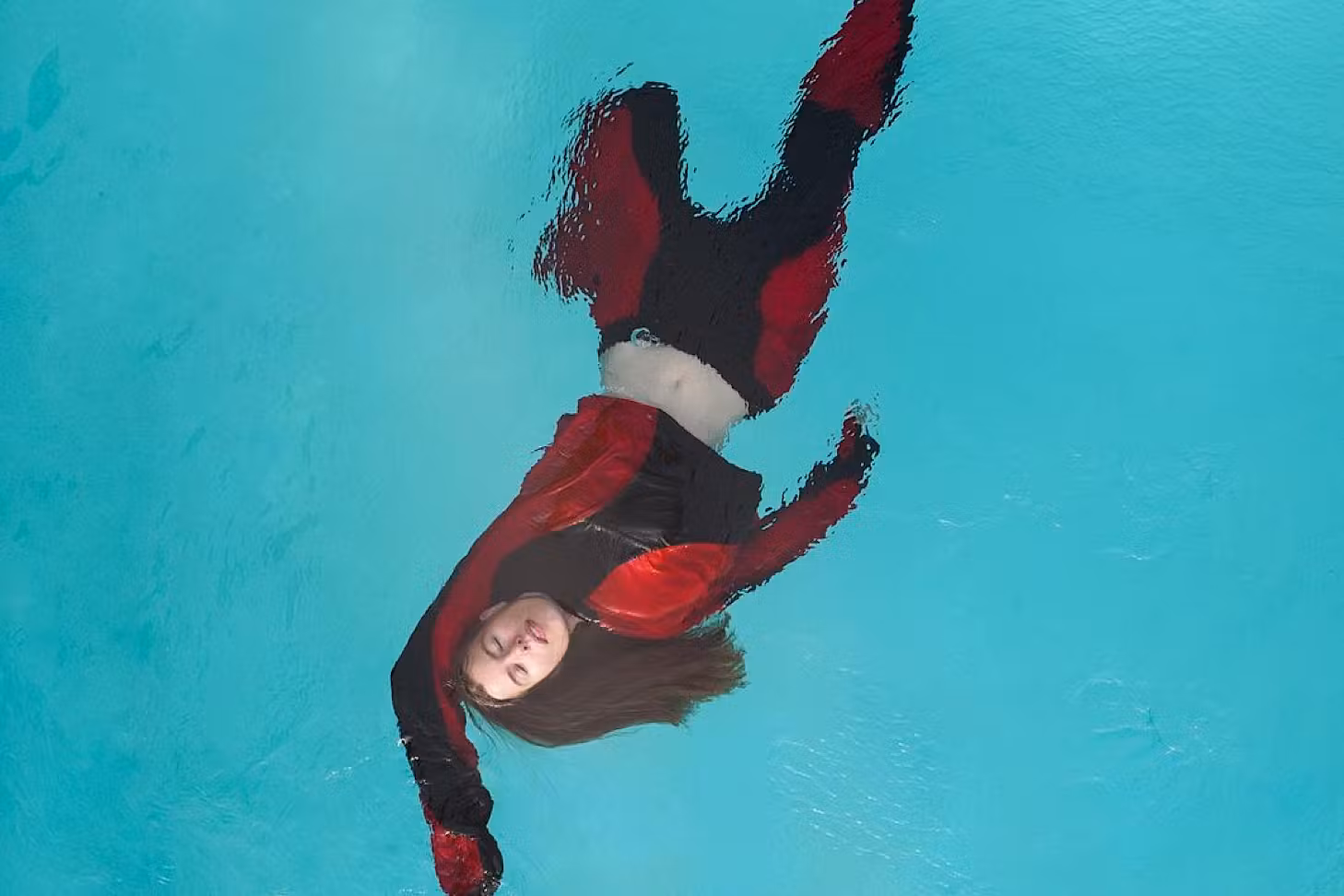 Hannah Lee Jade floats in a swimming pool wearing black and red threads.